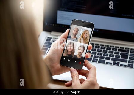Videoconferenza con un gruppo di persone. Giovane donna di affari che ha una videochattare con i colleghi sul suo telefono cellulare. Foto Stock