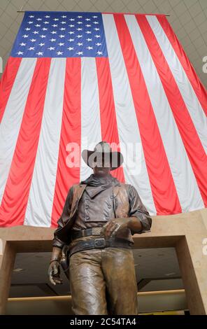 Una statua di John Wayne, di grandi dimensioni, con bandiera americana sullo sfondo, nell'aeroporto John Wayne. Santa Ana.Orange County.California.USA Foto Stock