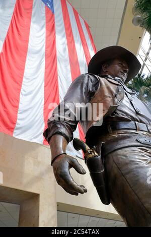 Una statua di John Wayne, di grandi dimensioni, con bandiera americana sullo sfondo, nell'aeroporto John Wayne. Santa Ana.Orange County.California.USA Foto Stock