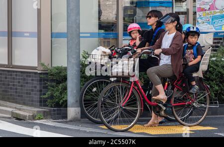 Madri giapponesi che cavalcano la bicicletta di utility di mammachari in via di Tokyo, Giappone. Foto Stock