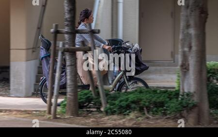 Madri giapponesi che cavalcano la bicicletta di utility di mammachari in via di Tokyo, Giappone. Foto Stock