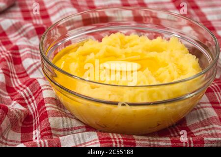 Patate spazzolate con burro fuso da vicino in una ciotola di vetro sul tavolo da cucina Foto Stock