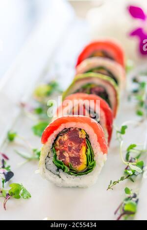 Rotolo di sushi maguro maki fresco. Un sushi in stile uramaki su un piatto bianco. Il pesce e il riso sashimi crudi sono all'esterno mentre nori è all'interno. Questo d Foto Stock