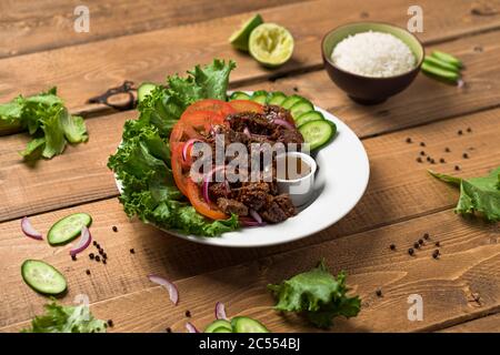 Bo Luc Lac insalata di manzo vietnamita. Chiamato anche Lok Lak in cambogia o scuotendo manzo in America. Gustosi cubetti di manzo saltato marinato vengono serviti con ingredienti freschi Foto Stock