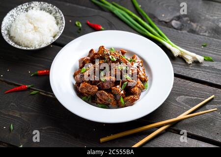Piatto di pollo Tso generale su sfondo scuro. Il pollo di General Tso (anche tsao o tao) è un popolare ristorante cinese con piatti croccanti fritti Foto Stock