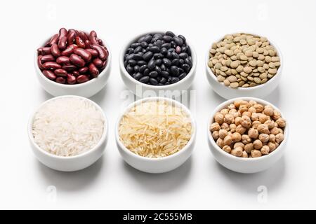 Ingredienti di riso e fagioli non cotti. Ciotola di riso basmati circondata da altre varietà di grani e legumi come: Ceci, fagioli rossi, gr Foto Stock