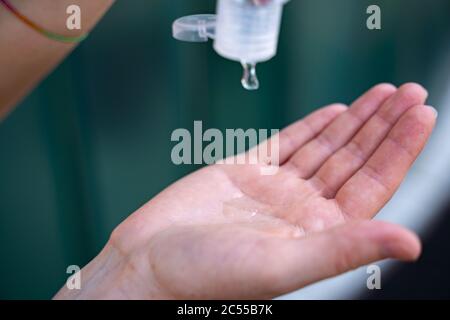Pulizia dell'igienizzatore per mani da versare femminile. Uso di gel antisettico con alcol per prevenire l'infezione Covid-19. Concetto di protezione pandemica del virus corona. Foto Stock