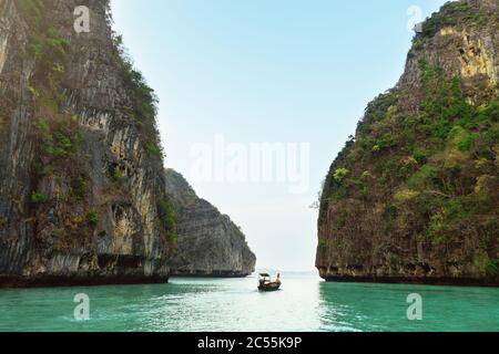 Paesaggio di una nave che naviga tra due rocce con vegetazione. Blu. Foto Stock