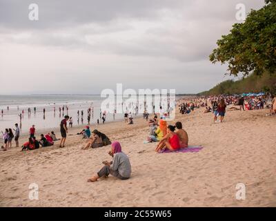 Kuta, Bali, Indonesia - 15 gennaio 2019: I turisti al tramonto si siedono su una popolare spiaggia turistica di Bali. Foto Stock