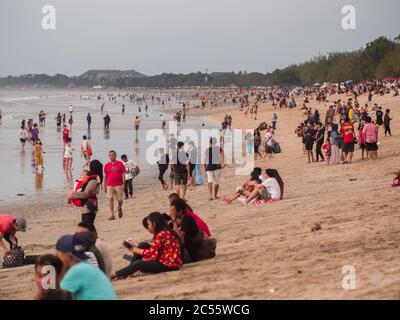 Kuta, Bali, Indonesia - 15 gennaio 2019: I turisti al tramonto si siedono su una popolare spiaggia turistica di Bali. Foto Stock