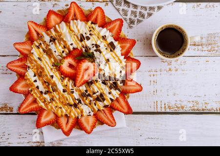 Caffè e fragola con torta di crosta panna montata su sfondo bianco di legno. Foto Stock