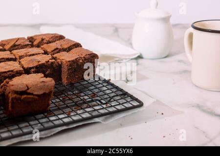 Brownie fatte in casa su griglia di raffreddamento su sfondo marmorizzato con tazza e spazio per la copia. Tasto alto Foto Stock