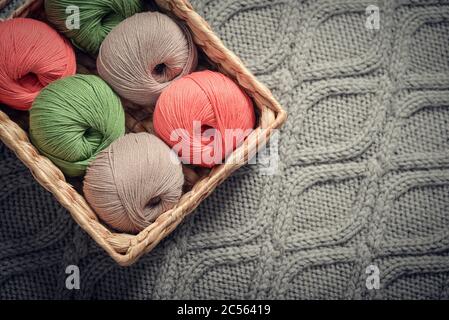 Palle di filato colorate in rustico cesto di vimini su closeup lettino blu Foto Stock