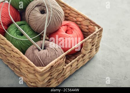 Palle di filato colorate in cesto di vimini su fondo grigio closeup Foto Stock