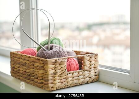 Palle di filato colorate in cesto di vimini sul davanzale nella chiusura domestica Foto Stock