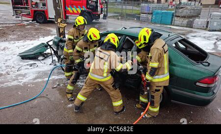 Team Off Firefighters cercando di tagliare la porta dell'auto aperta per salvare le persone coinvolte nell'incidente. Foto di alta qualità Foto Stock