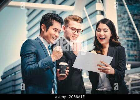Ritratto del team Aziende che alza le braccia festeggia su sfondo urbano sfocato. Concetto di successo aziendale. Foto Stock