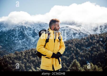 Giovane uomo con giacca gialla e zaino in montagna. Foto Stock