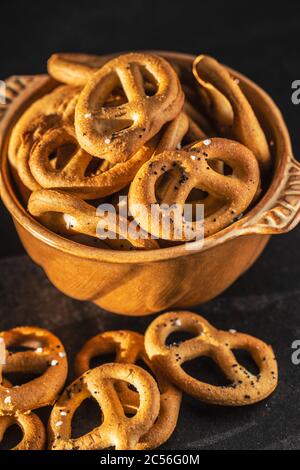 Pretzel salati croccanti in ciotola su tavola nera. Foto Stock