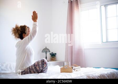 Yoga e sport sano attività fitness a casa - concetto di persone attive blocco quarantena - donna che fa meditazione consapevolezza nella camera da letto in Foto Stock