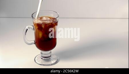 Versare il gelato su una tazza di caffè su sfondo bianco Foto Stock
