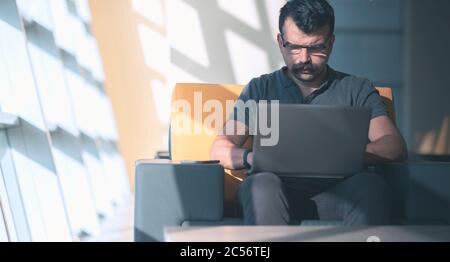 L'uomo concentrato tourtourtful sta scrivendo o preparando un rapporto via laptop Foto Stock