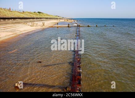 Una vista lungo la costa e la spiaggia in acque alte in una bella giornata estiva guardando verso Happisburgh, Norfolk, Inghilterra, Regno Unito. Foto Stock