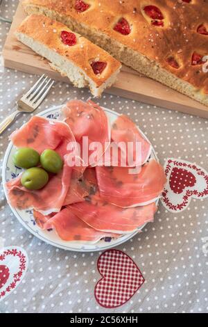 Focaccia pugliese fatta in casa, servita con prosciutto e olive di Parma, piatti tipici italiani Foto Stock