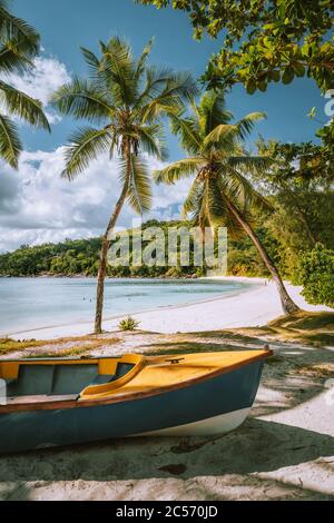 Barche sulla spiaggia esotica Takamaka con palme e laguna blu oceano sullo sfondo, l'isola di Mahe, Seychelles. Foto Stock