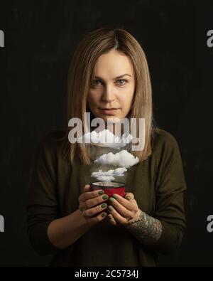 Ritratto donna che tiene la tazza di caffè con le nuvole Foto Stock