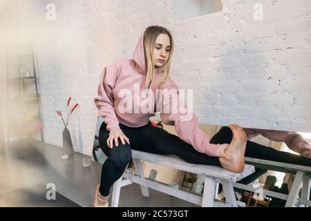 Giovane donna che allunga la gamba in studio di yoga Foto Stock