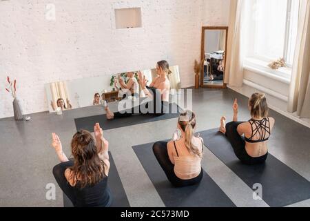 Istruttore di yoga e studenti che praticano in studio di yoga Foto Stock