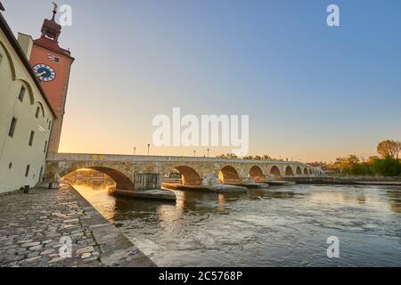 Vista del ponte di pietra sul Danubio dalla Historiische Wurstkuchl nella città vecchia alla luce della sera, Ratisbona, Baviera, Germania Foto Stock