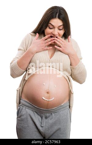 Donna incinta facendo un gesto sorpreso guardando il suo ventre come futuro concetto di mamma isolato su sfondo bianco Foto Stock