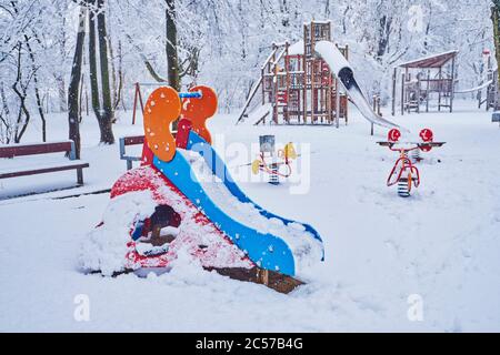 Cavallo a dondolo, scivolo, parco giochi, neve, inverno, Ratisbona, Baviera, Germania, Europa Foto Stock