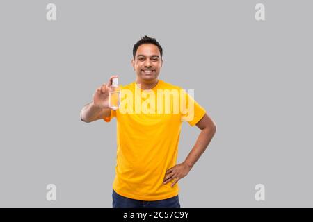 L'uomo indiano che mostra le mani igienizzante isolato. Uomo indiano che tiene antisettico della mano Foto Stock