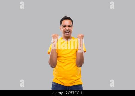 Indian Man molto felice ed eccitato, alzando le armi, celebrando una vittoria o successo. Firma del vincitore. L'uomo indiano isolato Foto Stock