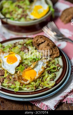 Piatto in padella, cavolo appuntito, manzo tritato, uova fritte da uova di quaglia Foto Stock