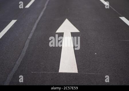 Immagine ad alto angolo dei cartelli stradali con freccia bianca sul asfalto Foto Stock