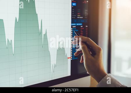 Primo piano di mano di uomo d'affari che punta alla tabella di mercato azionario e l'analisi sullo schermo del computer. Foto Stock