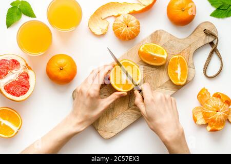 Mani che tagliano gli agrumi per il succo d'arancia Foto Stock