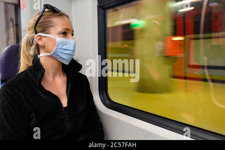 Donna con maschera facciale, siede in treno, riflessa in S-Bahn, crisi di Corona, Stoccarda, Baden-Württemberg, Germania Foto Stock