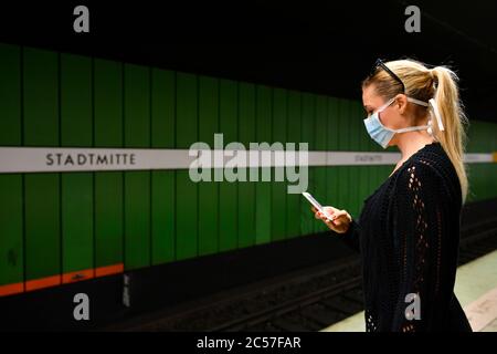 Donna con maschera facciale, telefono cellulare, in attesa di treno, S-Bahn, stazione Stadtmitte, crisi Corona, Stoccarda, Baden-Württemberg, Germania Foto Stock