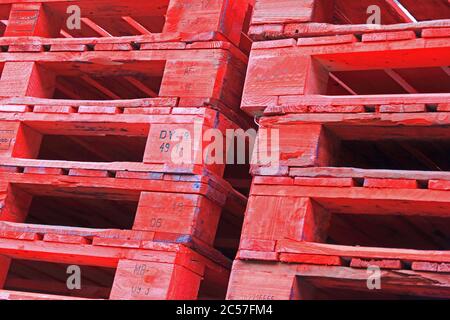 Pila di pallet in legno verniciato rosso Foto Stock