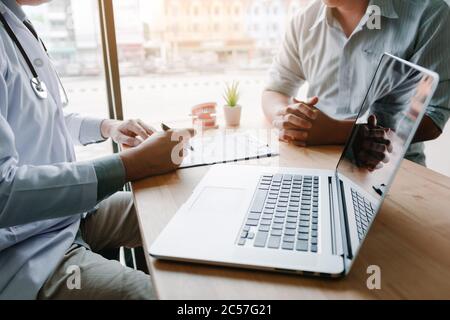 I dentisti asiatici tengono una penna che spiega i problemi dei loro denti e i trattamenti futuri o la chirurgia. Foto Stock