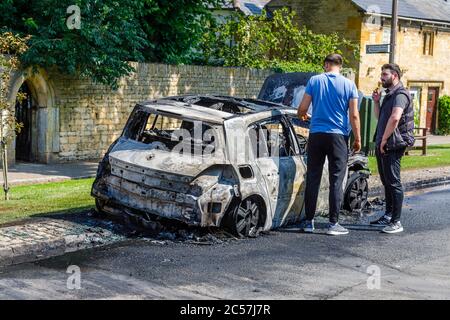 Un'auto completamente bruciata sul lato della strada in High Street, Chipping Campden, una piccola città di mercato nel Cotswolds in Gloucestershire Foto Stock