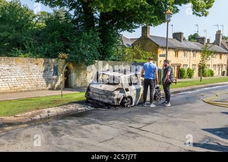 Un'auto completamente bruciata sul lato della strada in High Street, Chipping Campden, una piccola città di mercato nel Cotswolds in Gloucestershire Foto Stock