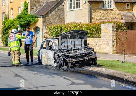 Un'auto completamente bruciata sul lato della strada in High Street, Chipping Campden, una piccola città di mercato nel Cotswolds in Gloucestershire Foto Stock
