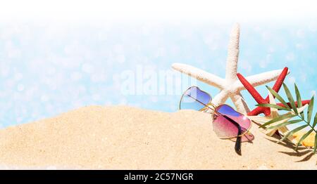 Occhiali da sole con stelle marine e foglie di palma sulla sabbia della spiaggia Foto Stock
