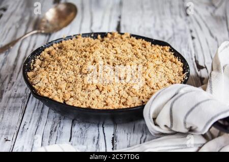 Dolce casa BlackBerry e Cobbler mirtillo cotto in una padella di ghisa e sormontato con una farina d'avena dorata croccante su un rustico tavolo di legno bianco. Selezionare Foto Stock